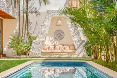 a house with a swimming pool and palm trees at Villa Aztec - 6BDR private pool and garden in Seminyak