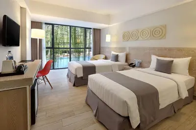 a hotel room with two beds and a television at Hotel NEO+ Kuta Legian by ASTON in Legian