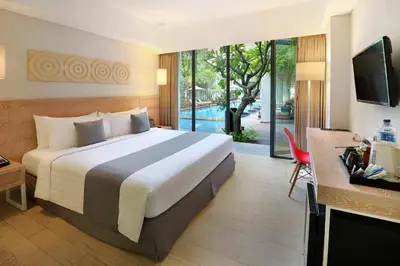 a hotel room with a large bed and a television at Hotel NEO+ Kuta Legian by ASTON in Legian