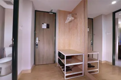 a bathroom with a toilet and a wooden door at Hotel NEO+ Kuta Legian by ASTON in Legian