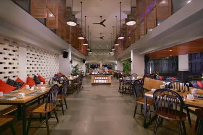 a restaurant with wooden tables and chairs in a room at Hotel NEO+ Kuta Legian by ASTON in Legian