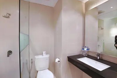 a bathroom with a toilet and a sink and a mirror at Hotel NEO+ Kuta Legian by ASTON in Legian