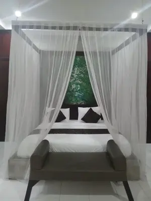 a bedroom with a canopy bed with a window at Village Pool Private In Kuta Bali in Legian