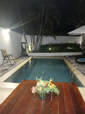 a table in front of a swimming pool at night at Village Pool Private In Kuta Bali in Legian