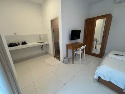 a bedroom with a bed and a desk and a mirror at Jabu Hasian Bali in Kerobokan