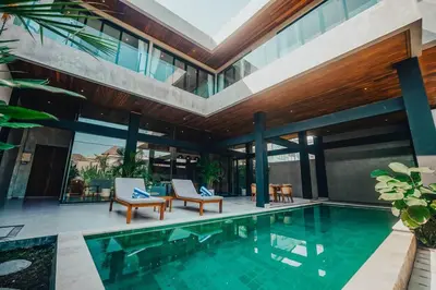 an indoor swimming pool with two chairs and a house at Villa Cintamu - Modern Spacious Villa in Prime Berawa Location in Canggu