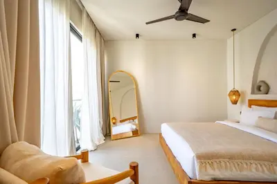 a bedroom with a bed and a mirror and a ceiling fan at Casanna Umalas in Canggu