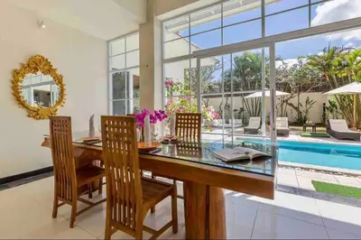 a dining room with a glass table and chairs and a pool at Spacious 2bdr Seminyak walking eat&shop street in Seminyak