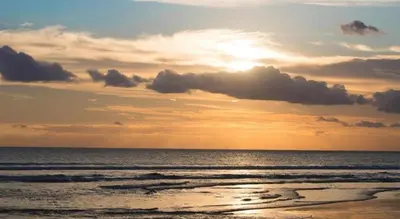 a sunset on a beach with the ocean at Asoka City Bali Hotel in Legian