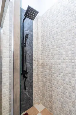 a shower in a bathroom with a stone wall at Rumah Kodel in Legian in Seminyak