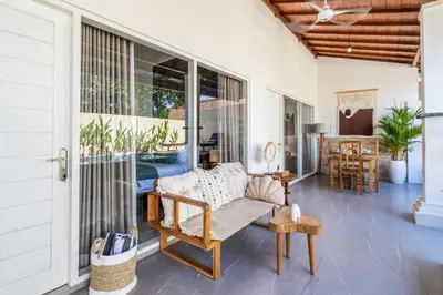 a screened porch with a couch and a table at Rumah Kodel in Legian in Seminyak