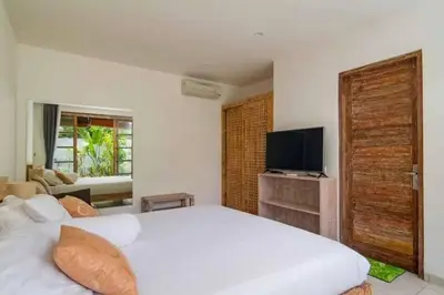 a bedroom with a large white bed and a television at Villa Catta Seminyak in Legian