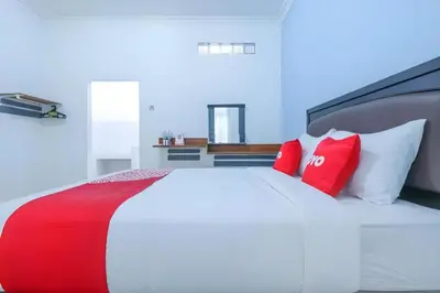 a bed with red and white pillows in a room at OYO 1755 De'balcon Accomodation Near Ngurah Rai Airport in Ngurah Rai International Airport
