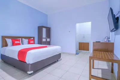 a bedroom with a bed with red pillows and a table at OYO 1755 De'balcon Accomodation Near Ngurah Rai Airport in Ngurah Rai International Airport