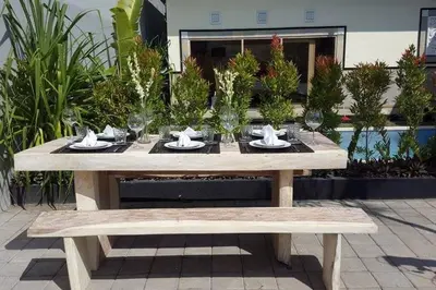 a wooden picnic table with glasses and a bench at Sol Bella Villa 2 in Seminyak