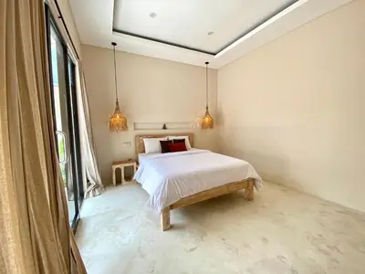 a bedroom with a bed and two pendant lights at Luminara villa in Canggu