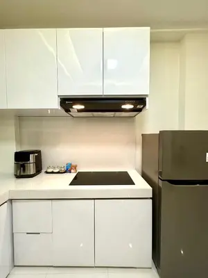 a kitchen with white cabinets and a black refrigerator at Villa Noeul Seminyak - Fast Wifi And Private Pool in Seminyak
