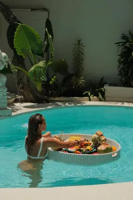 a woman in a swimming pool with a tray of food at Villa Malicott Athena - 3C in Seminyak