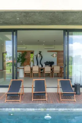 two chairs sitting next to a swimming pool in a house at Villa Amanora & Amaluna - 2 Stunning Villas, 9 Bedrooms for Groups in Canggu