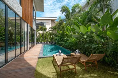 a swimming pool in a house with two chairs and a table at Villa Amanora & Amaluna - 2 Stunning Villas, 9 Bedrooms for Groups in Canggu
