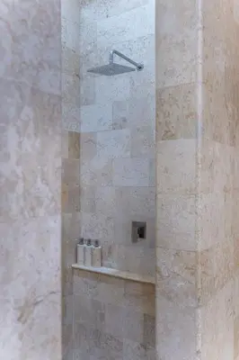 a bathroom with a shower with a stone wall at Rumah Impian Villa by Betterplace in Canggu