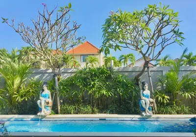 two statues of women sitting on the side of a swimming pool at Ayu Guest House 2 in Canggu