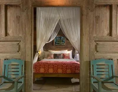 a bedroom with a canopy bed with two blue chairs at Villa Mamoune in Umalas