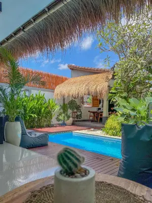 a resort with a swimming pool and a straw umbrella at Bubble Villa & Rice field view in Kerobokan