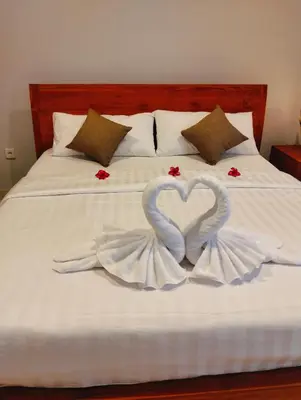 two swans are forming a heart on a bed at De Jaya in Kerobokan