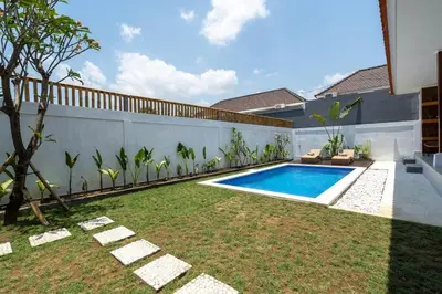 a backyard with a swimming pool and a fence at Umanala - 5 Min To Beach, Sleek Villa with Spacious Pool Area in Kerobokan