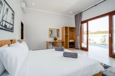 a bedroom with a white bed and a large window at Umanala - 5 Min To Beach, Sleek Villa with Spacious Pool Area in Kerobokan
