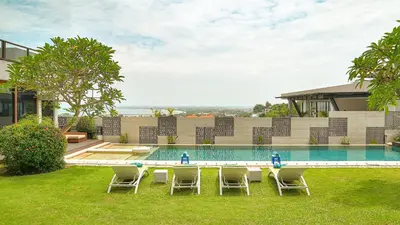 a pool with chairs and a table in the grass at Villa Aiko in Jimbaran