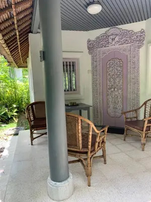 a porch with chairs and a table and a pole at Poppies Cottages on Two in Legian