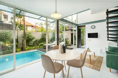 a living room with a table and chairs and a pool at Villa De Luca By Aishwarya International in Umalas