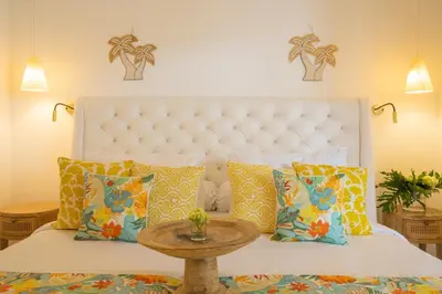 a bedroom with a white bed with pillows and a table at Casa Elias Seminyak in Seminyak