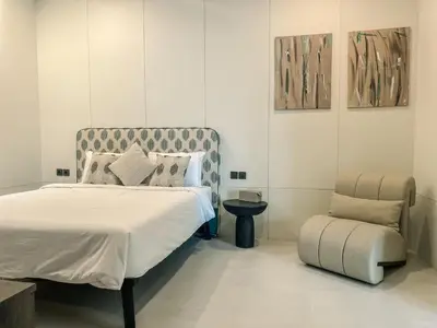 a bedroom with a bed and a chair at Cara Villa Bali in Seminyak