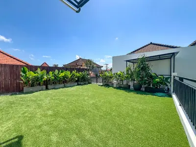 a backyard with green grass and a fence at Cara Villa Bali in Seminyak