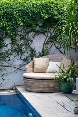 a wicker chair sitting on a patio next to a pool at Viki Nest by SooBali 4BR in Umalas