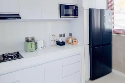 a kitchen with a black refrigerator and white cabinets at Wakajima House Kerobokan by The Lavana in Kerobokan