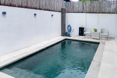 a swimming pool with two chairs and a table at Wakajima House Kerobokan by The Lavana in Kerobokan