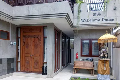 a building with a wooden door and a wooden bench at Wakajima House Kerobokan by The Lavana in Kerobokan
