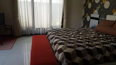 a bedroom with a large bed with a red rug at Kubu Nesa in Jimbaran