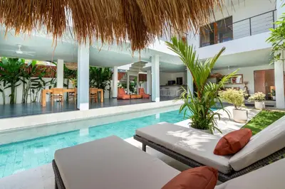 a swimming pool with a chaise lounge and a villa at Beautiful modern villa in the heart of Seminyak in Seminyak