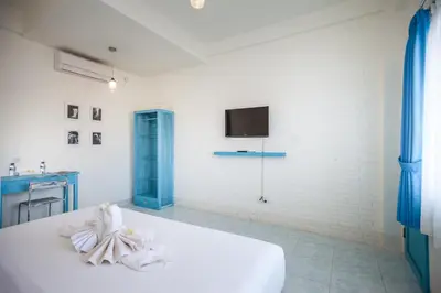 a white room with a bed and a tv on a wall at Paras Paros Marina Lodge in Sanur