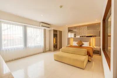 a large bedroom with a bed and a couch at Kuta Angel Hotel in Kuta