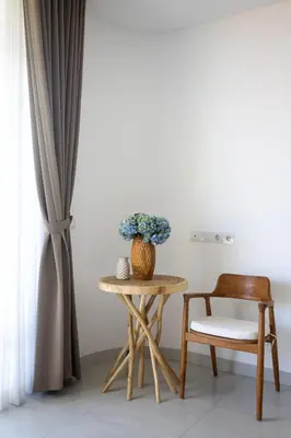 a table with a chair and a vase with blue flowers at Villa Harper by BaliSuperHost in Canggu