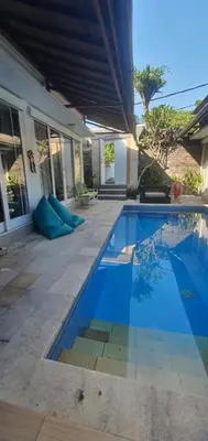 a swimming pool in front of a house at Lily Villa in Seminyak