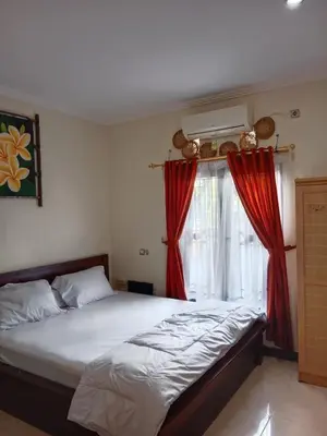 a bedroom with a bed and a window with red curtains at Nyoman bali house villa in Seminyak