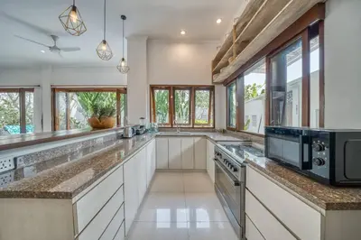 a large kitchen with white counter tops and windows at Villa Ima in Canggu