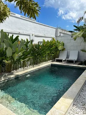 a swimming pool with two chairs in front of a building at Baliview homestay in Umalas